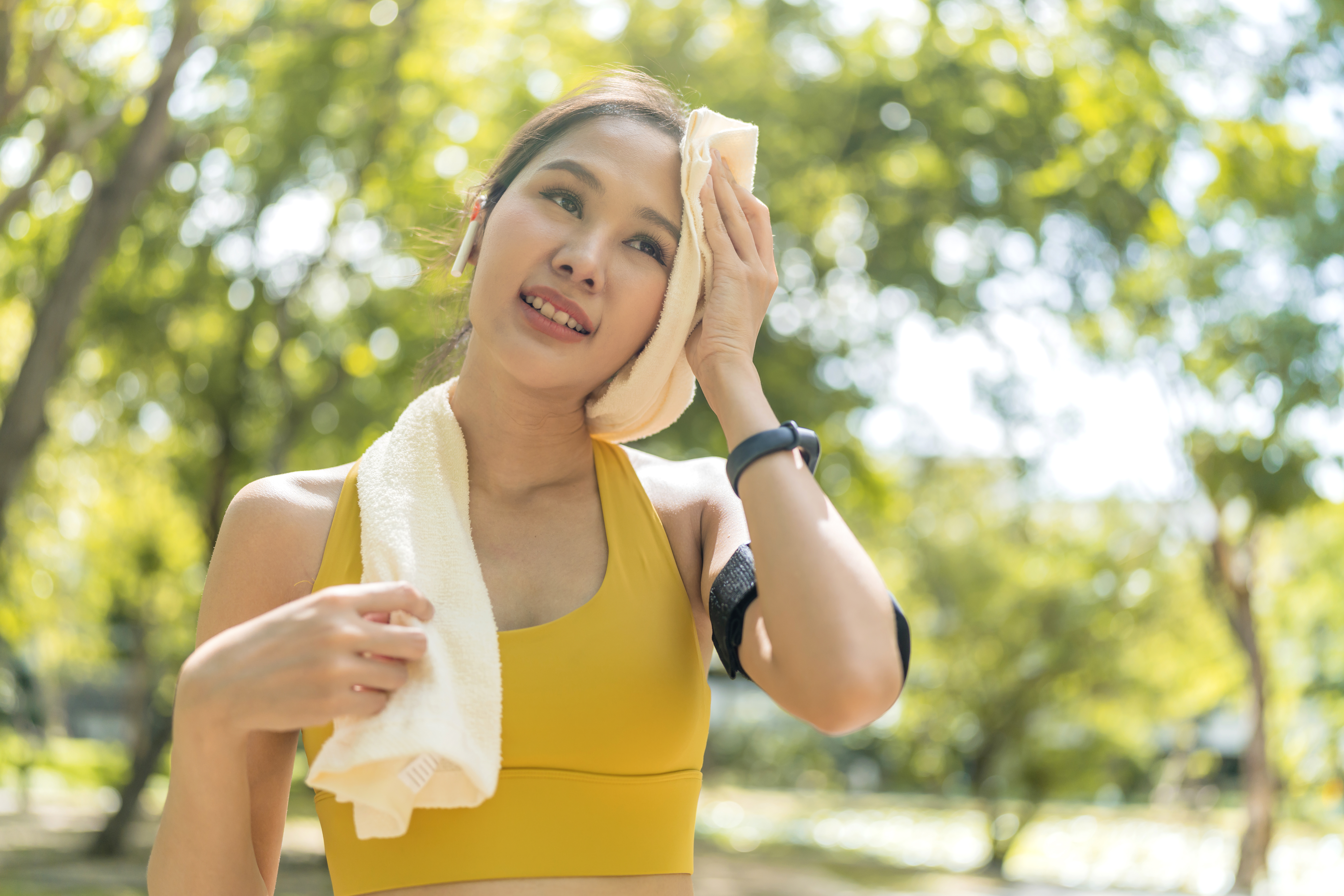 Asian active Female runner workout standing bent over and catching her breath after a running session in the park garden. Sports female woman taking break after a run in morning exercise lifestyle